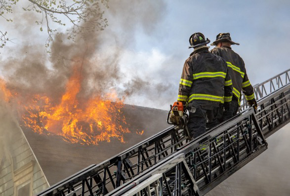 Two firefighters next to a burning house