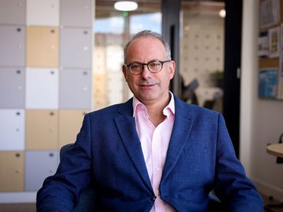Dan Leader, a man in a blue jacket, pink shirt and glasses