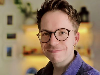 Adam Barber smiling wearing round glasses